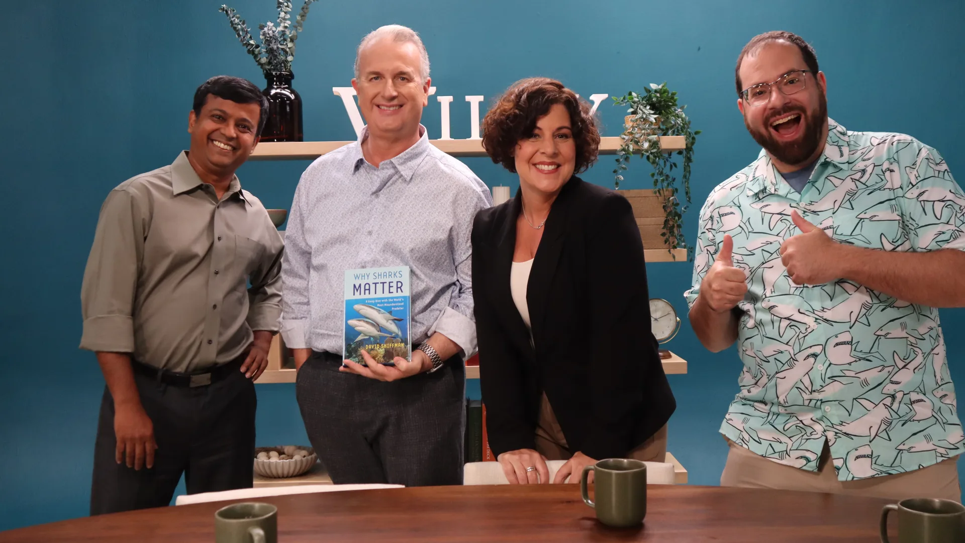 Four guests smiling with a book on the Wiley Conversations set