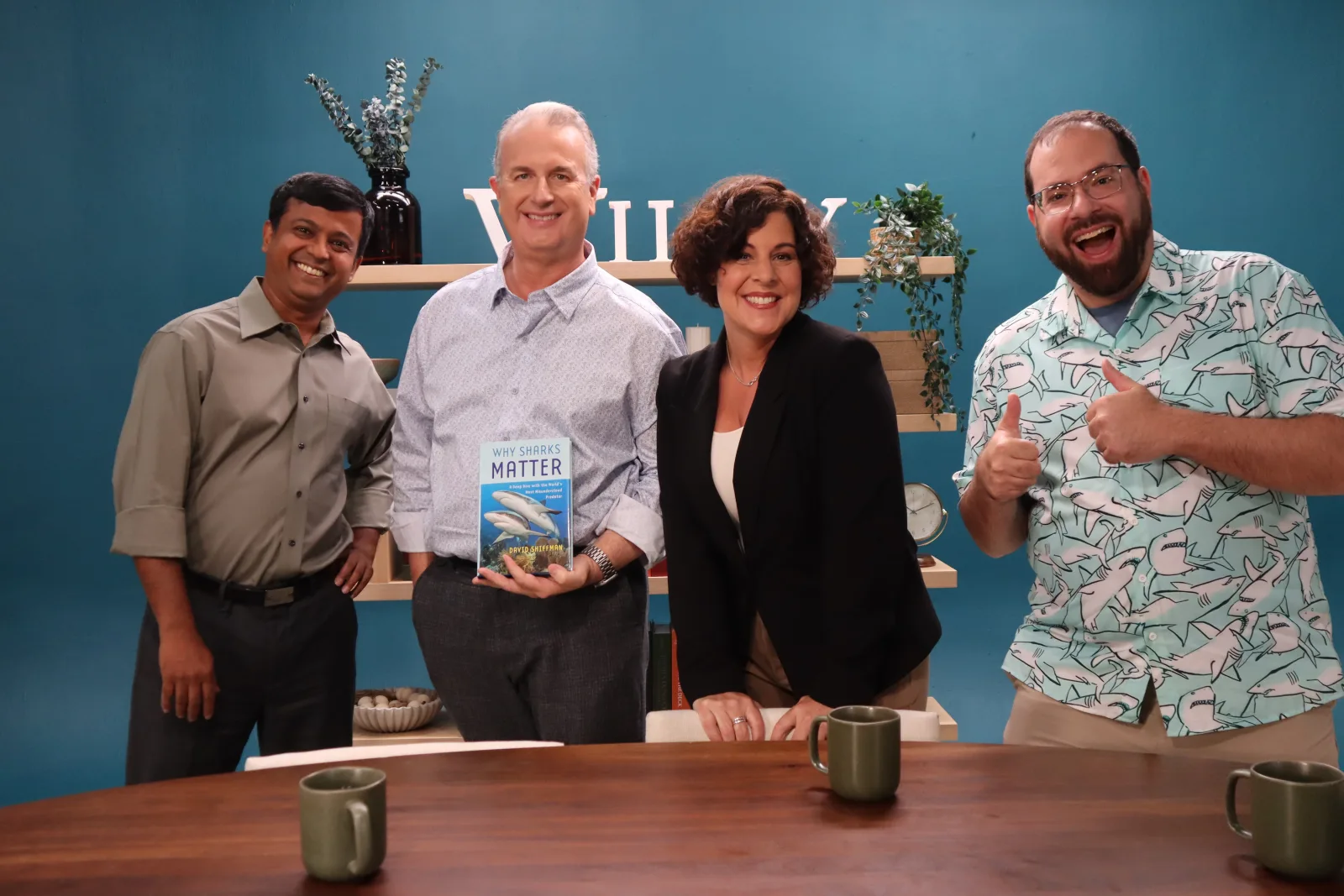 Four guests gathered around a book on the Wiley Conversations set